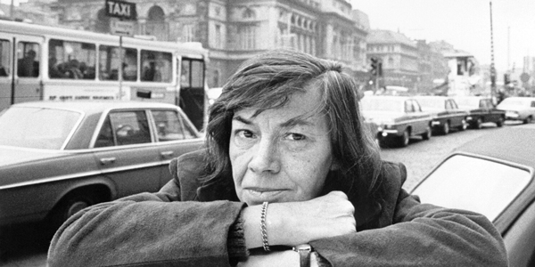 Patricia_Highsmith_resting_on_forearms_streetscene_behind