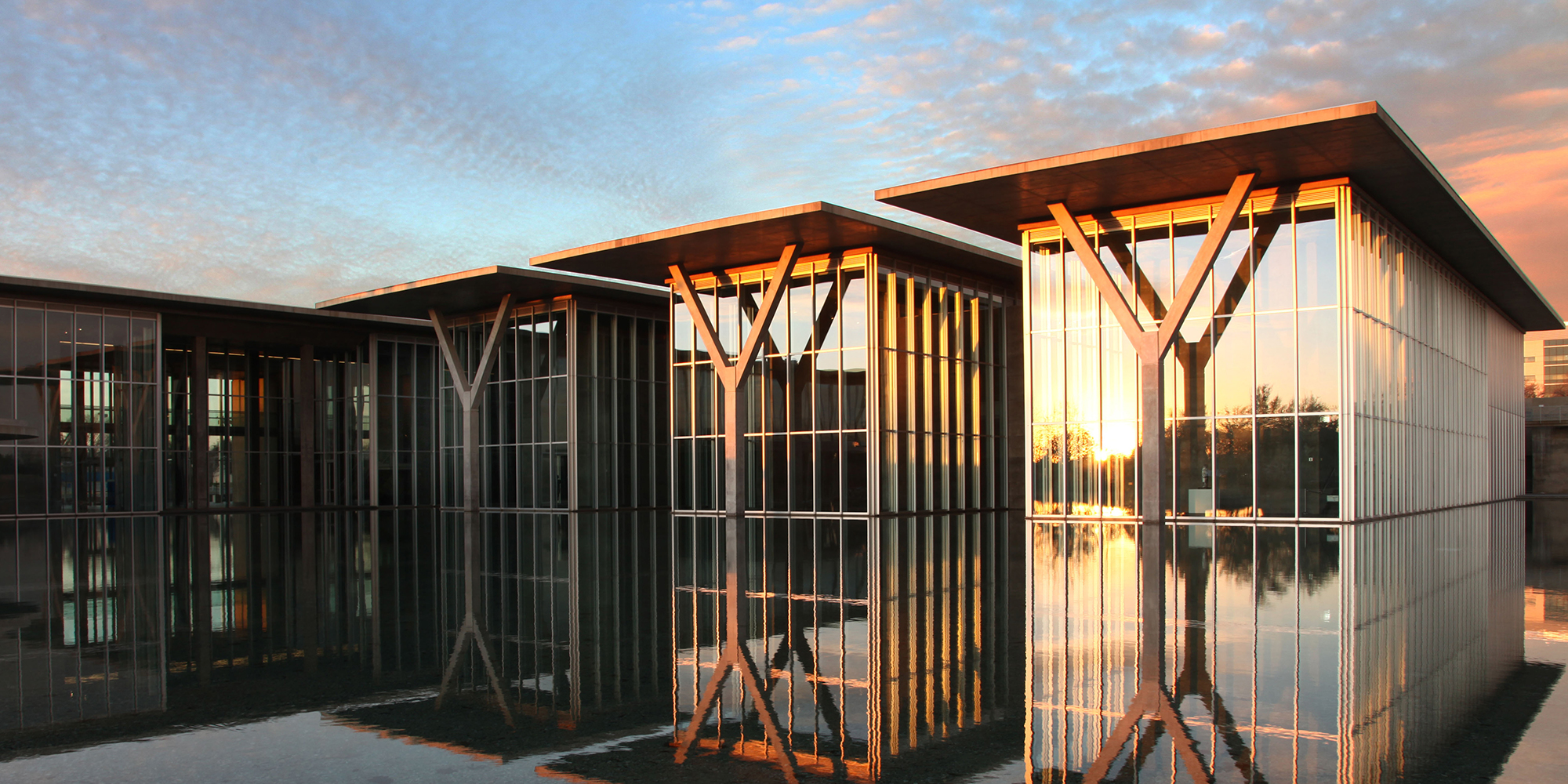 Glass, steel, and concrete building with reflecting pond