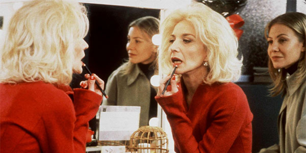 Blonde woman applying lipstick in mirror