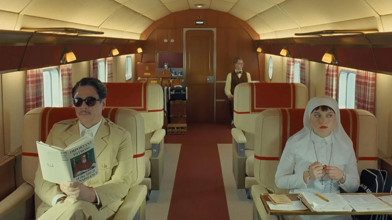 Man in yellow suit and nun sitting in a train car