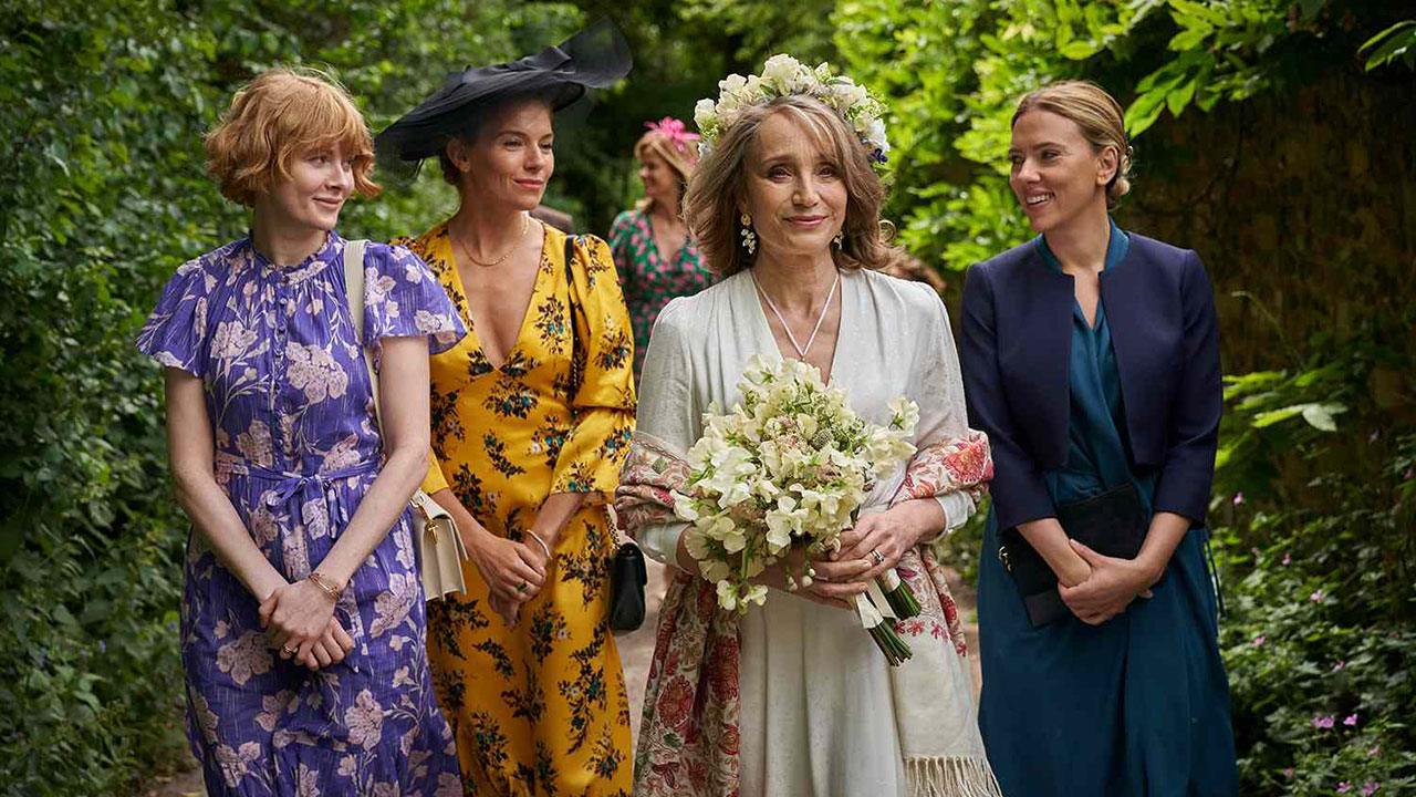Three adult daughters surrounding their mother who is in a wedding dress