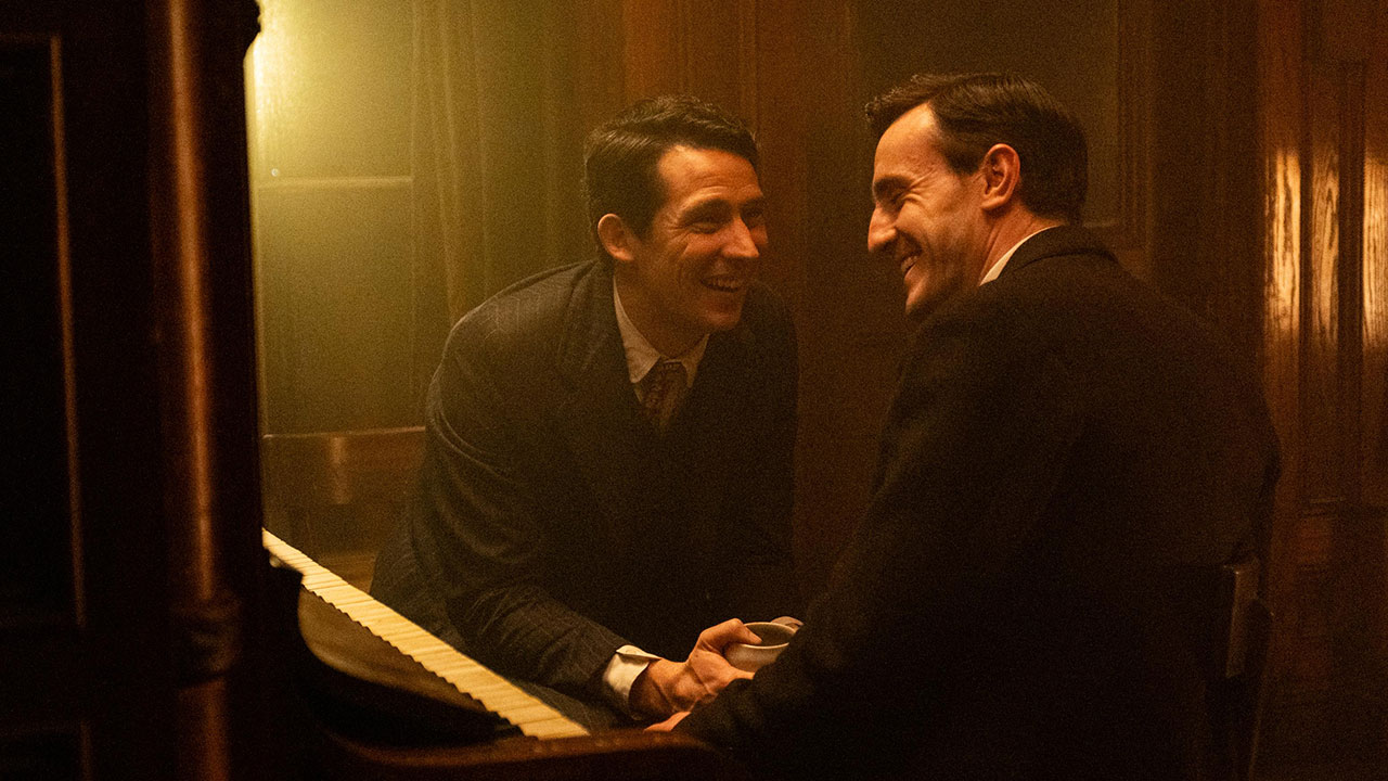 Two men facing each other and laughing in a dimly lit wooden space