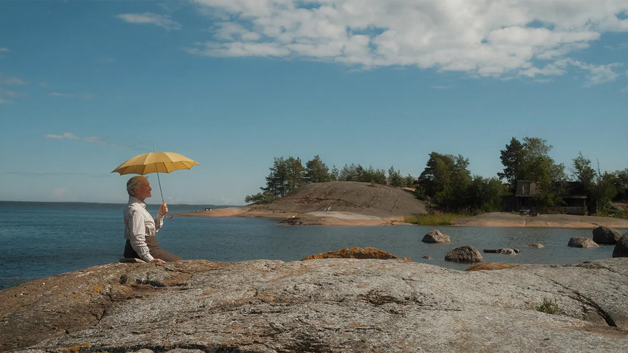 Woman with umbrella on rocky sea shore