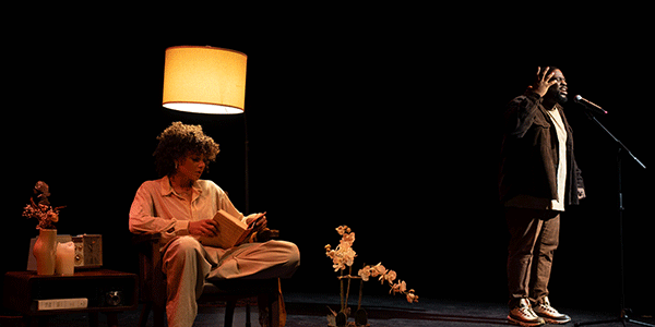 Man singing and woman sitting in chair by lamp