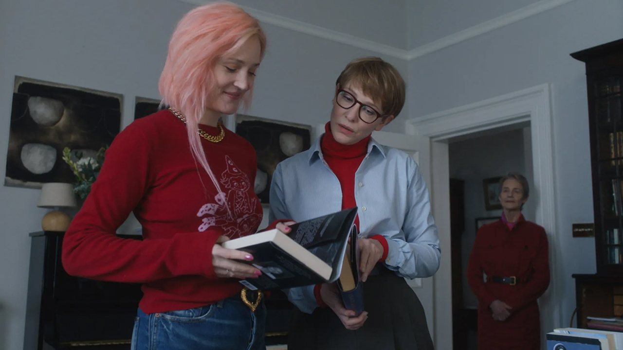 Teenage daughter with pink hair showing mother book in bedroom