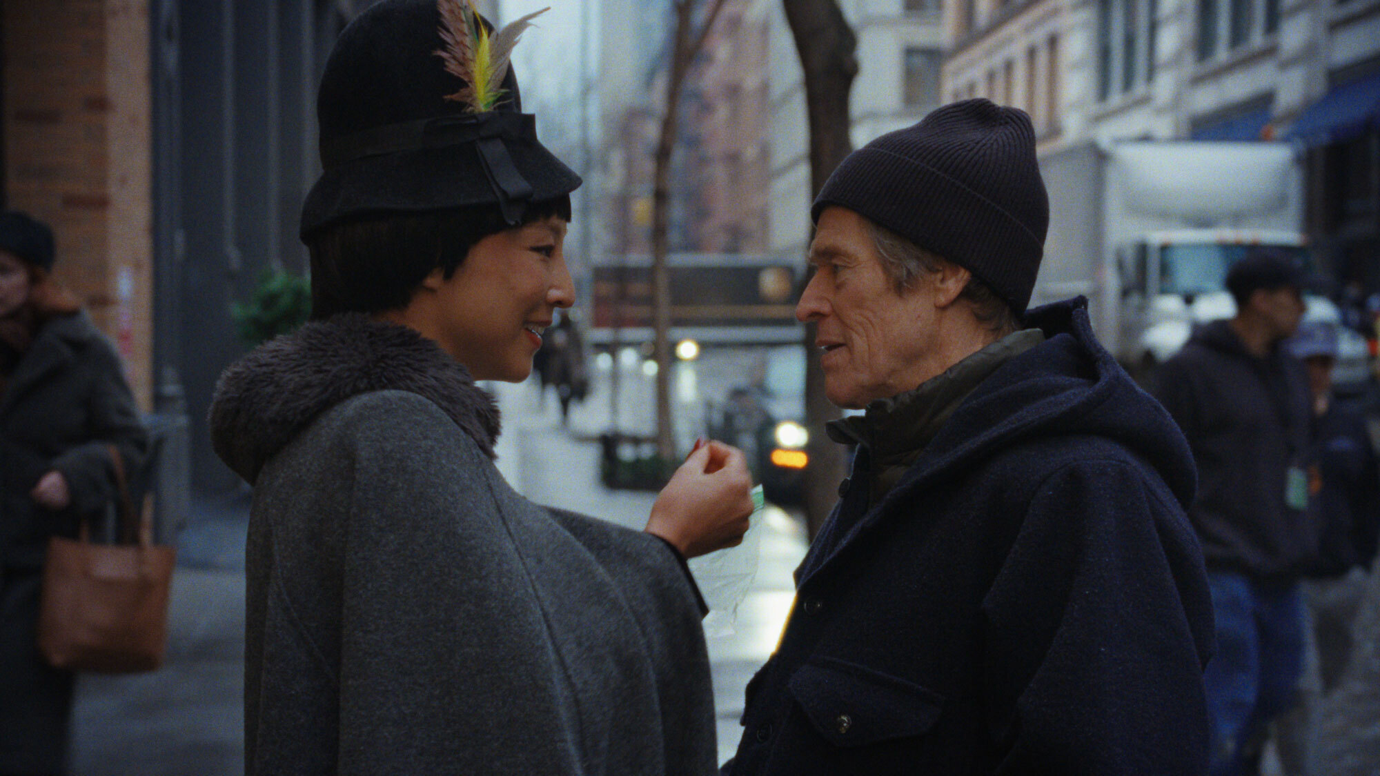 Elegantly dressed young Asian woman gesturing to older white man directly in front of her on a New York street on a cold day