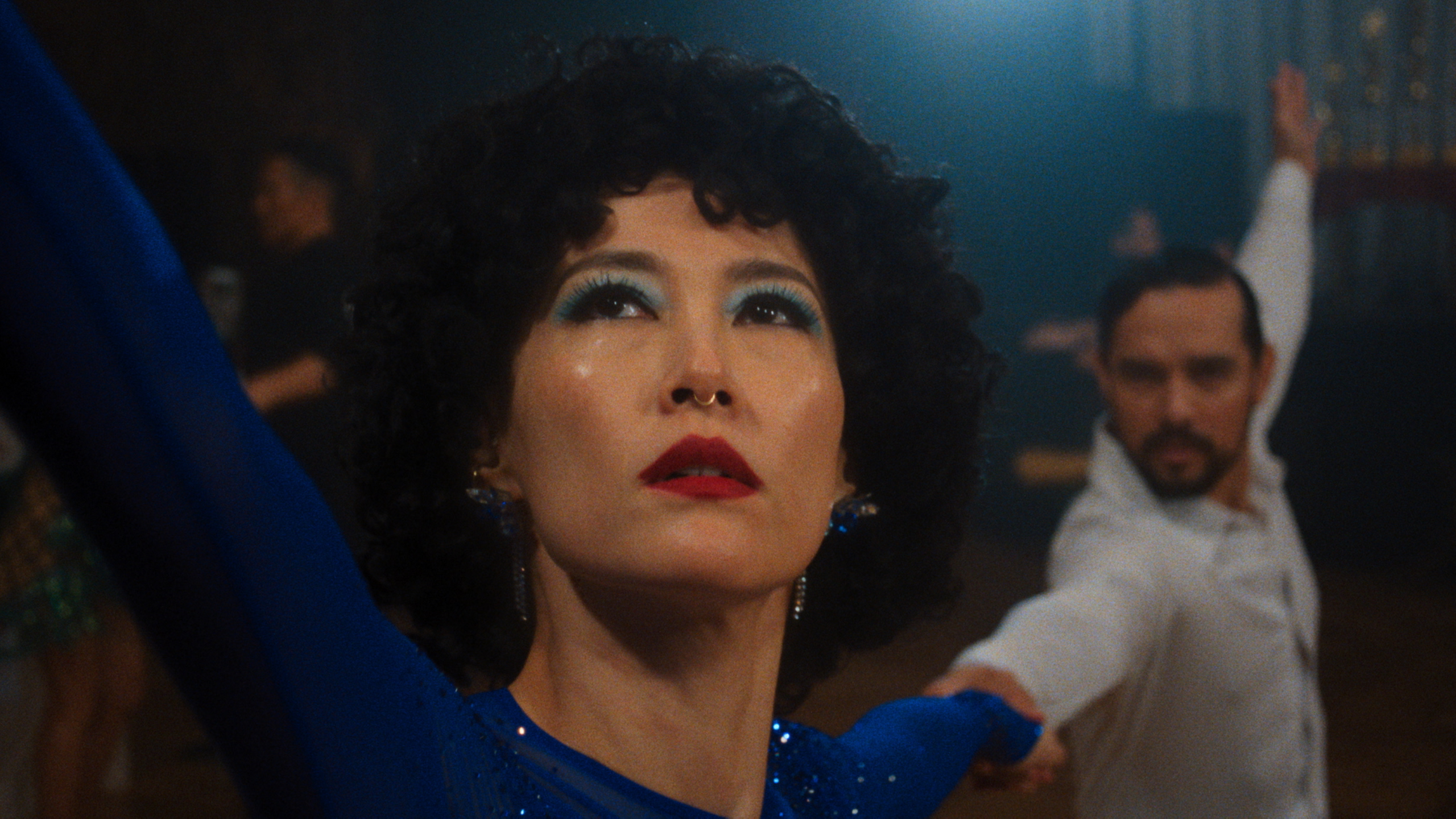 A female Asian ballroom dancer with blue eyeshadow looking up
