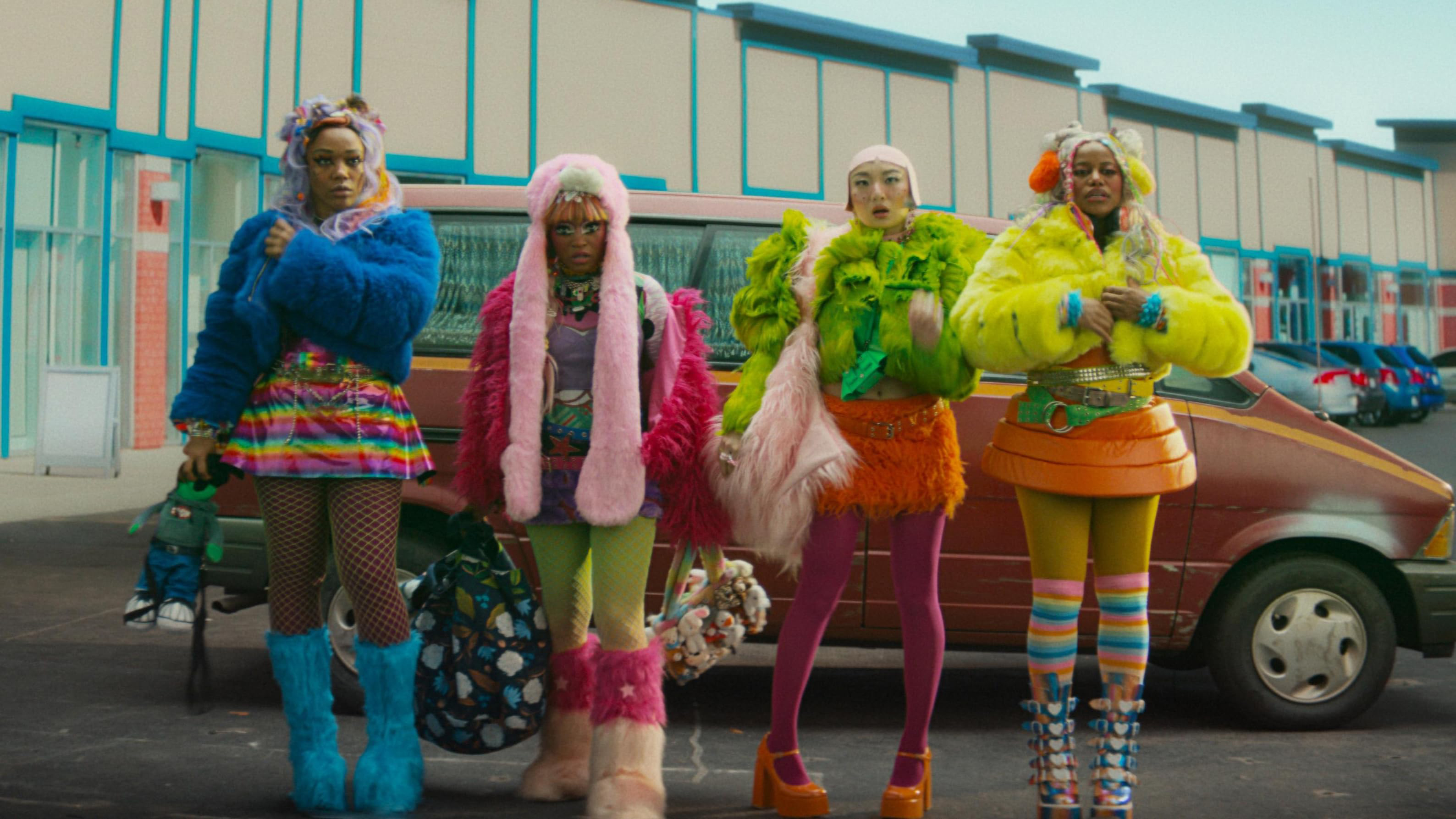 Four colorfully dressed women standing in front of a mini van