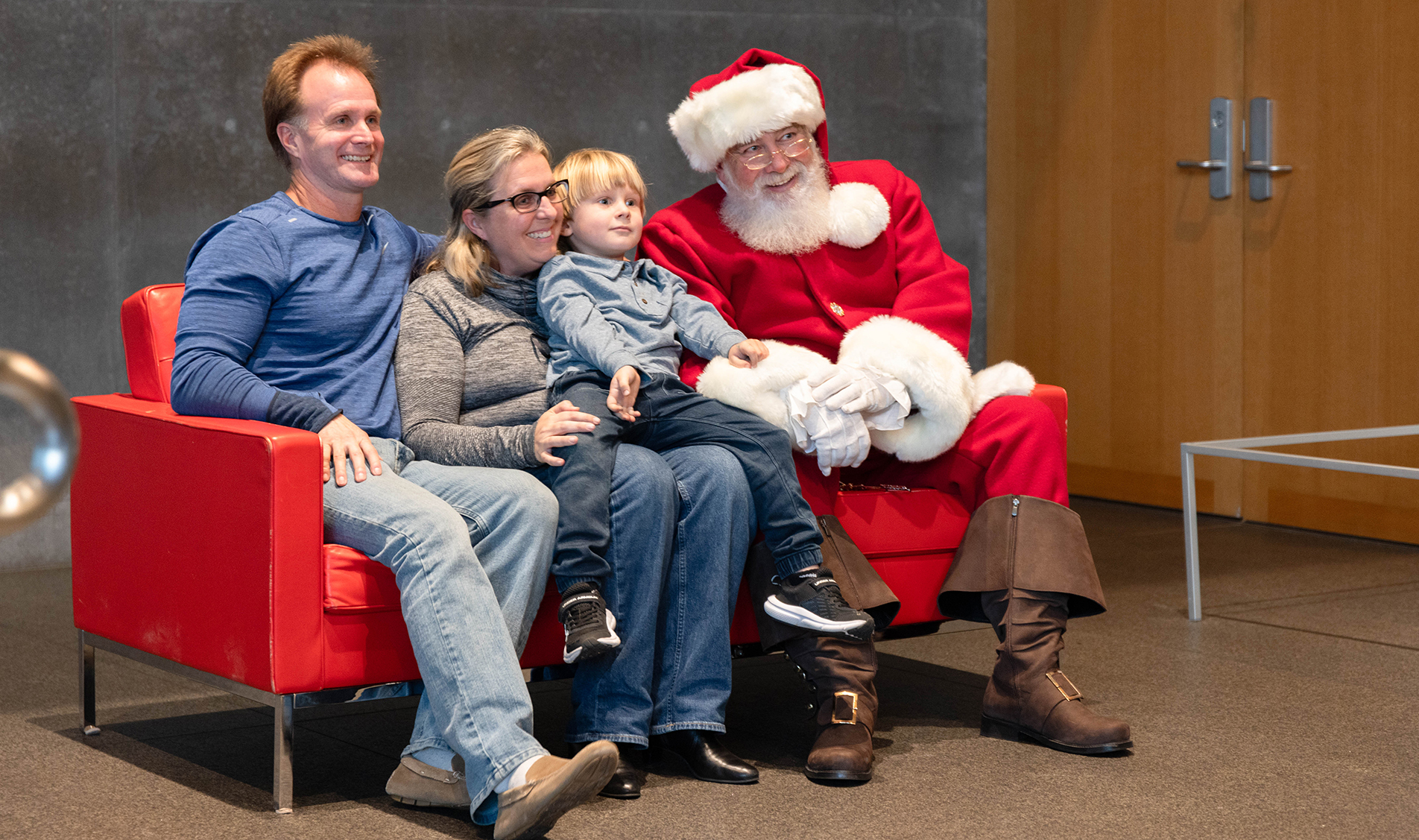 A family with Santa on a red couch