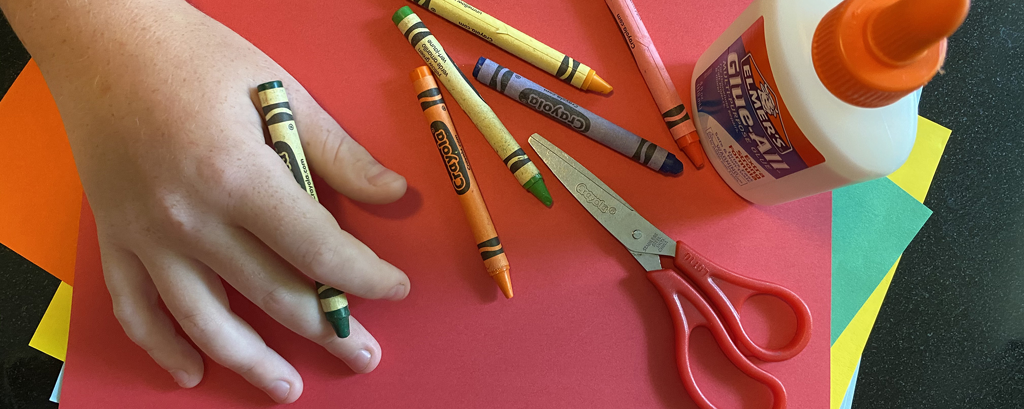 childs_hand_coloring_with_crayons_on_construction_paper